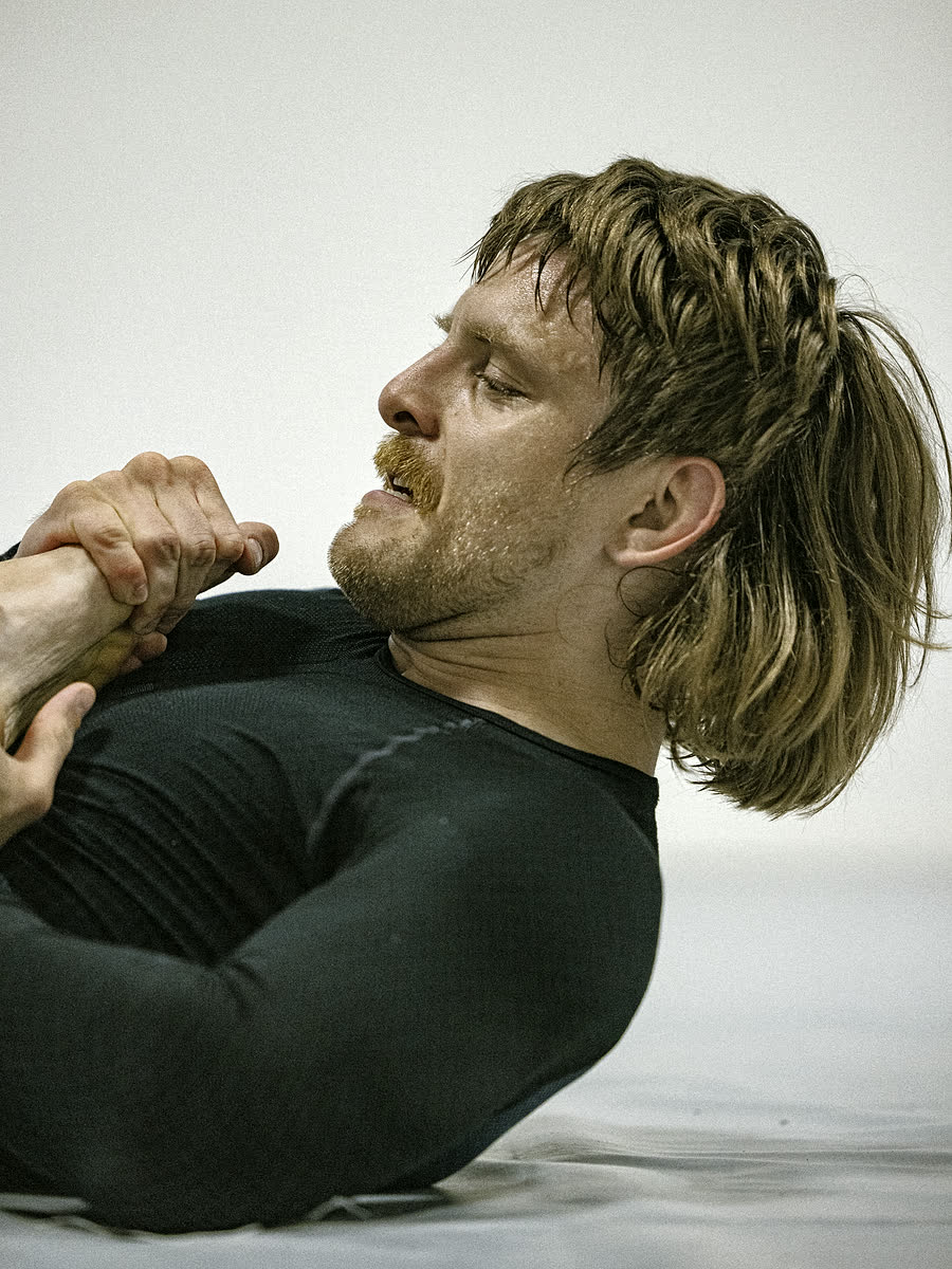 Utøver i svart rashguard sitter på matta etter en runde no-gi.